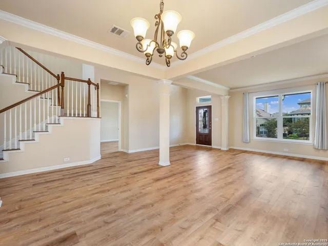 a view of an empty room with wooden floor and a chandelier