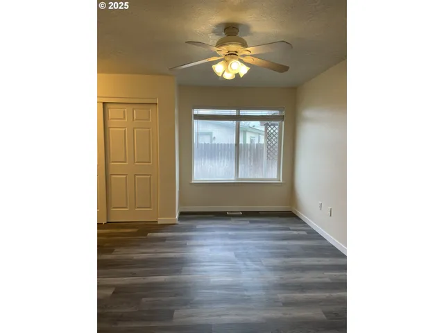 a view of an empty room with window and wooden floor