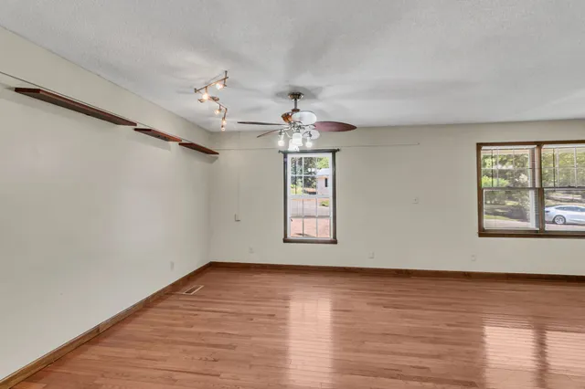 a view of an empty room with wooden floor and a window