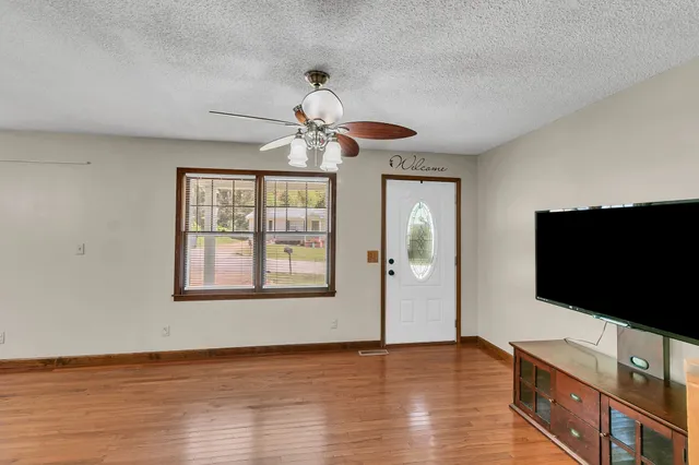 a view of a livingroom with a flat screen tv wooden floor and chandelier fan