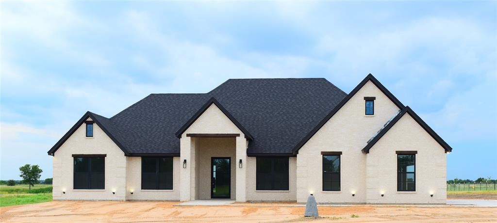 View of front facade featuring roof with shingles and brick siding