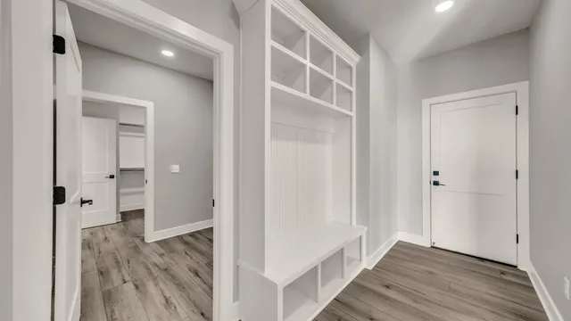 a view of a hallway with wooden floor and closet area