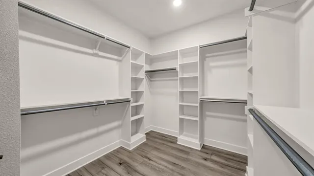 a walk in closet with wooden floor