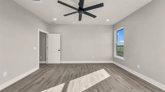 an empty room with wooden floor and windows
