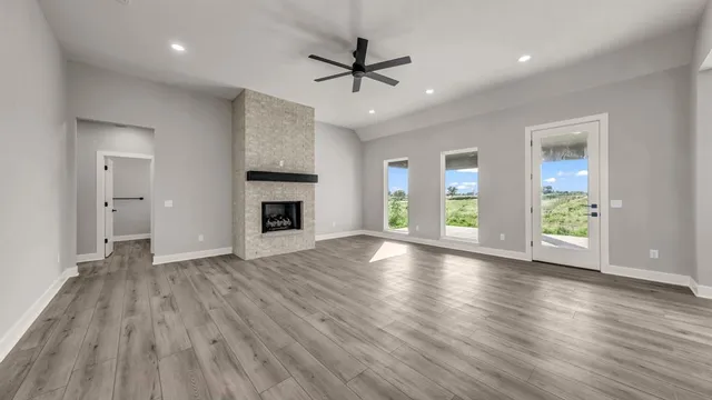 an empty room with wooden floor a ceiling fan and windows