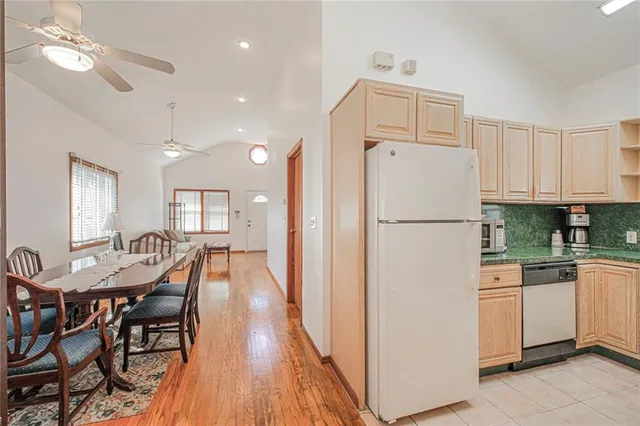 a kitchen with stainless steel appliances granite countertop a refrigerator a stove a sink a dining table and chairs with wooden floor