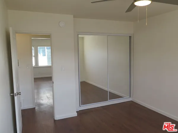 an empty room with wooden floor closet and windows