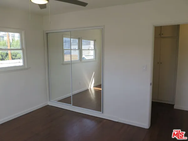 an empty room with wooden floor cabinet and windows