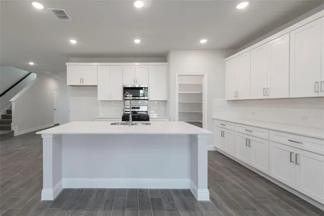 a kitchen with kitchen island white cabinets and stainless steel appliances