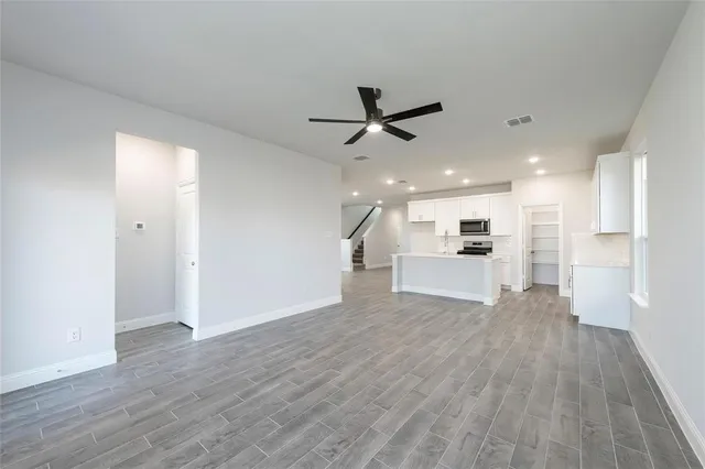 a view of empty room with wooden floor and kitchen view