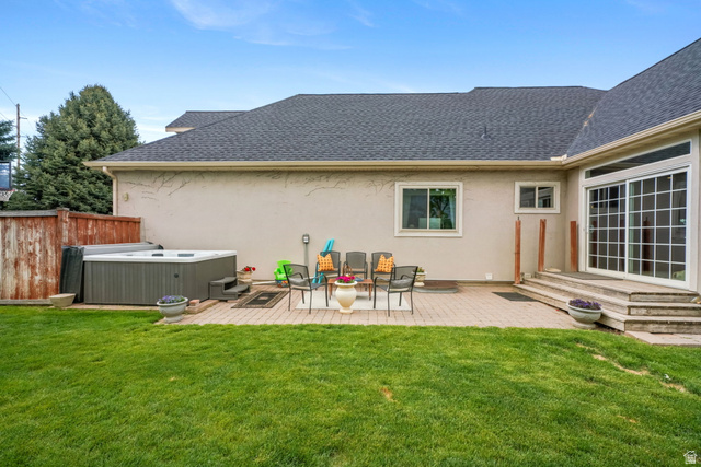 357 South 320 W Street Lindon, UT 84042 - Photo 38 of 41 Spacious backyard featuring a paver patio with a built-in hot tub, mature lawn, stucco exterior, and sliding glass doors with transom windows