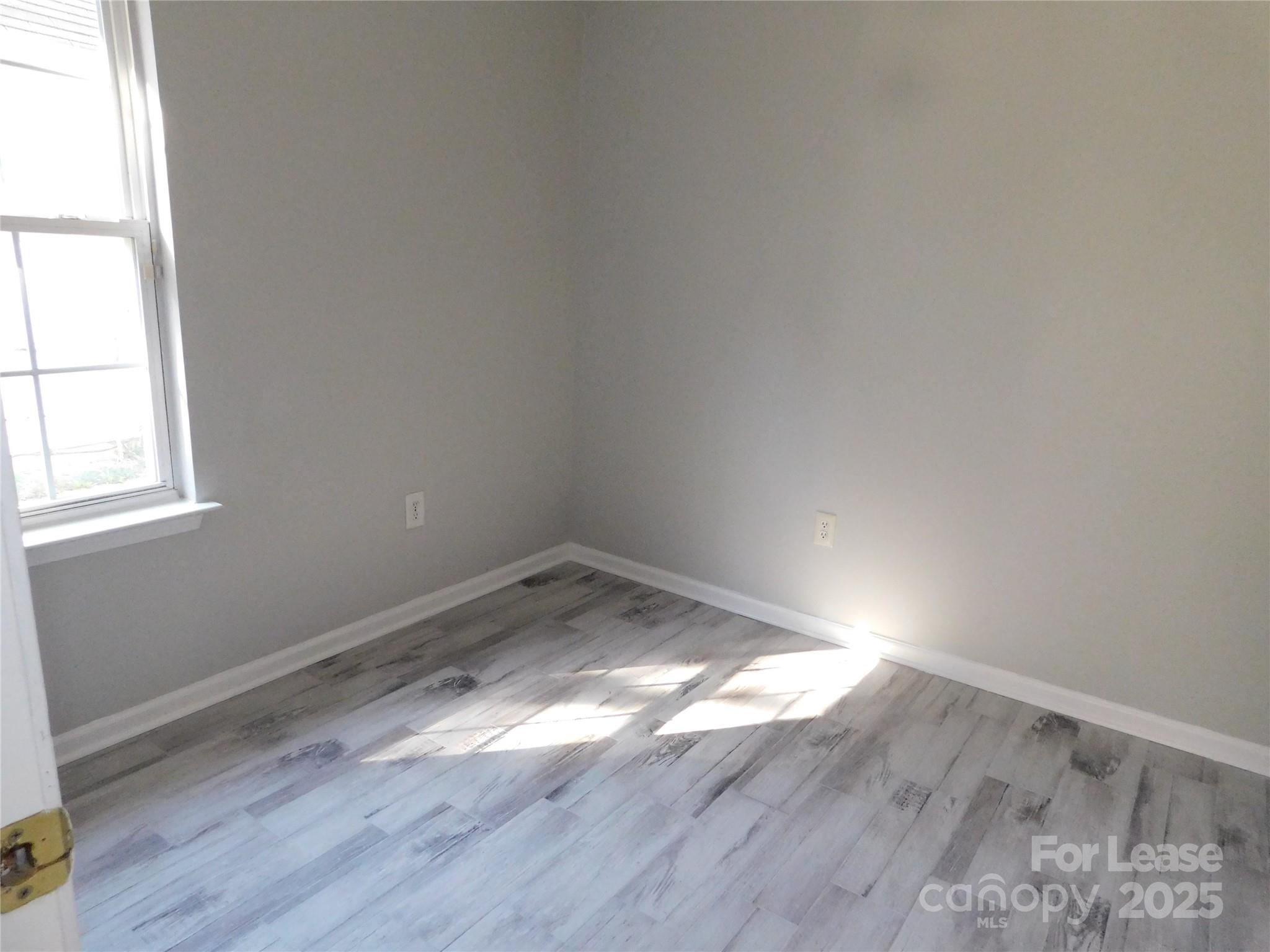 1119 Hannah Rae Court Charlotte, NC 28214 - Photo 13 of 19 an empty room with wooden floor and windows