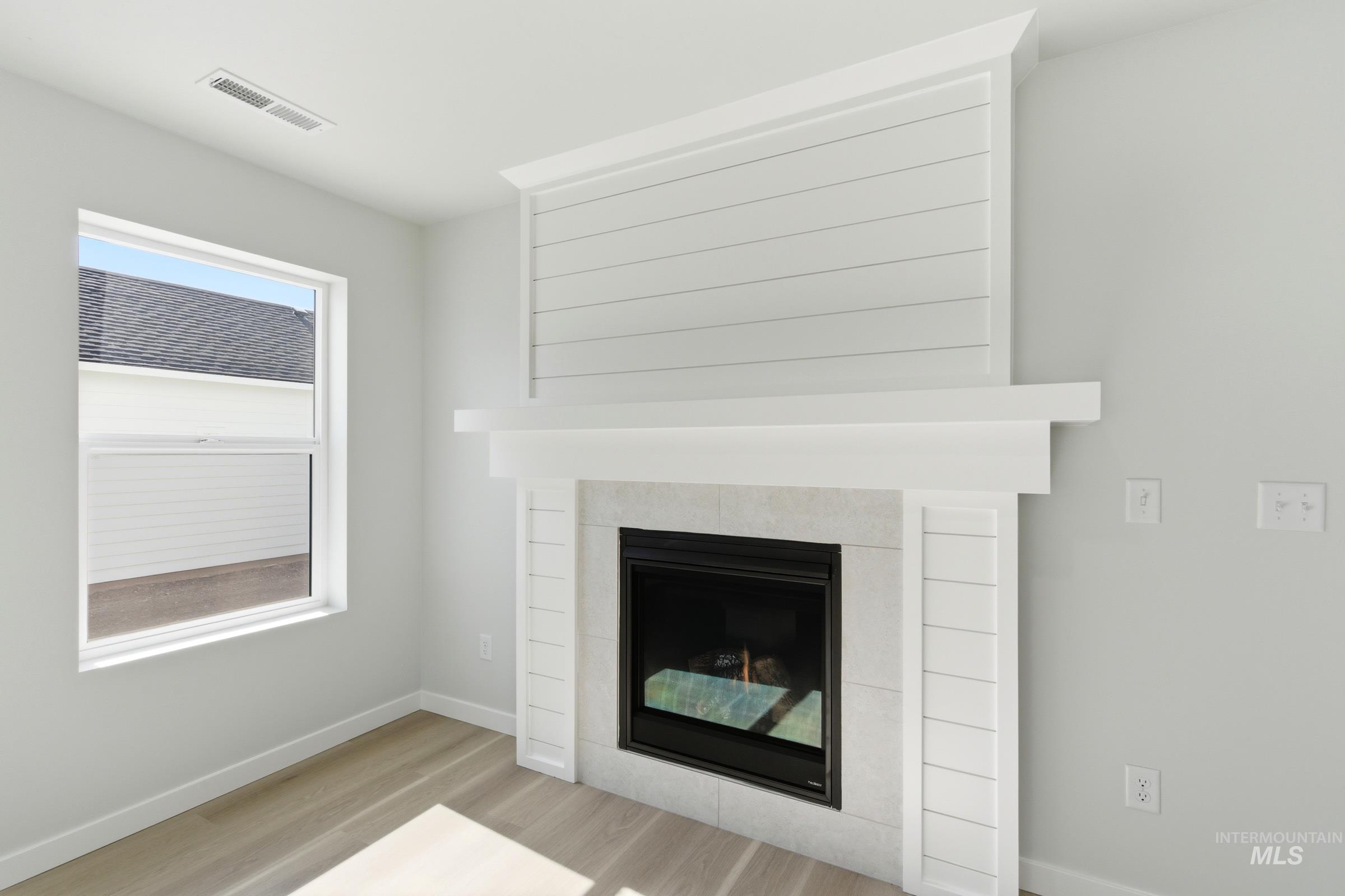 13677 Redway Court Caldwell, ID 83607 - Photo 12 of 35 Fireplace featuring a shiplap surround and a stone-look tile hearth