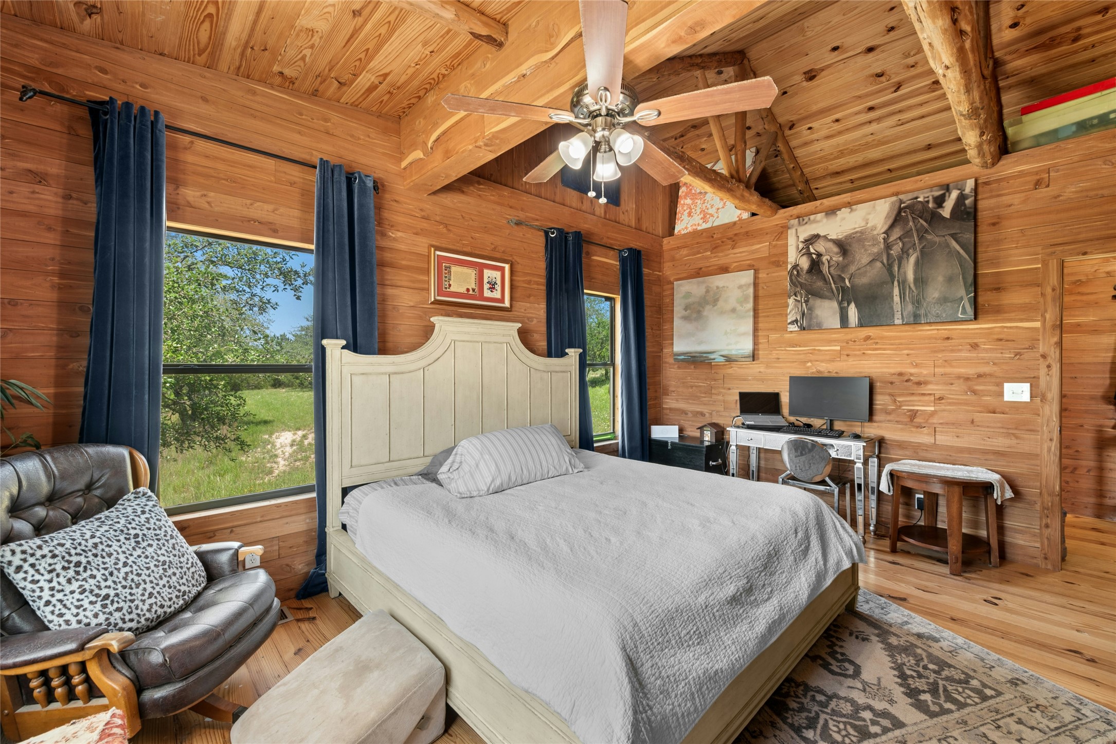 496 Middleton Road Spicewood, TX 78669 - Photo 21 of 40 Wood-paneled room featuring a vaulted wood-beam ceiling, wood-finish flooring, a ceiling fan with integrated lighting, and multiple windows