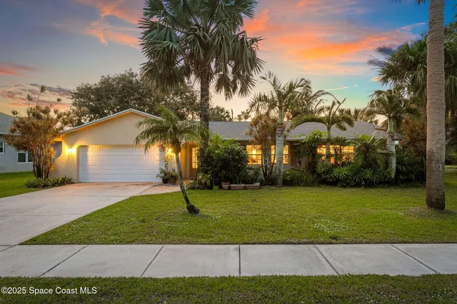 a view of a house with a yard and palm trees