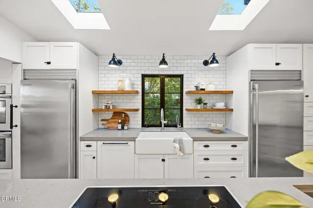 a kitchen with stainless steel appliances kitchen island granite countertop a sink and a refrigerator
