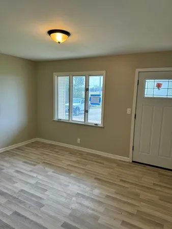 a view of an empty room with wooden floor and a window