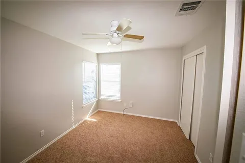 an empty room with windows and fan