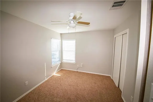 an empty room with windows and fan