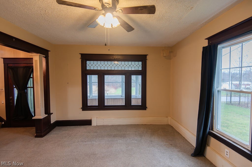 1195 South Johnson Road Sebring, OH 44672 - Photo 10 of 34 Carpeted spare room with a textured ceiling, ornate columns, and a ceiling fan