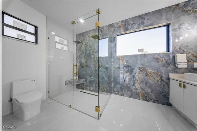 a bathroom with a granite countertop sink a toilet and shower