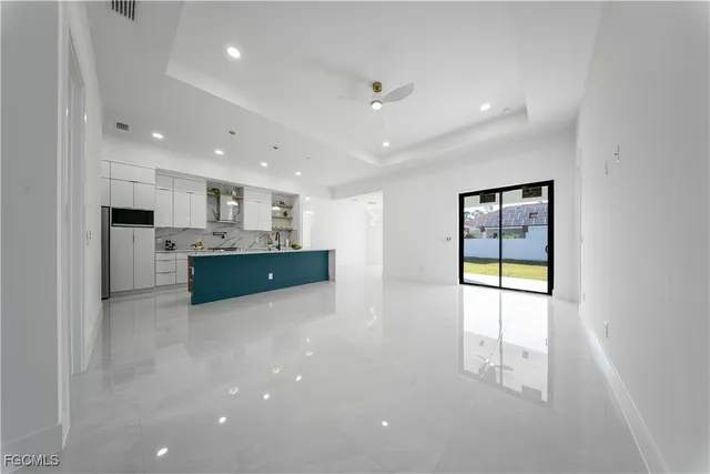 a large white kitchen with kitchen island a sink a stove and a refrigerator with wooden floor