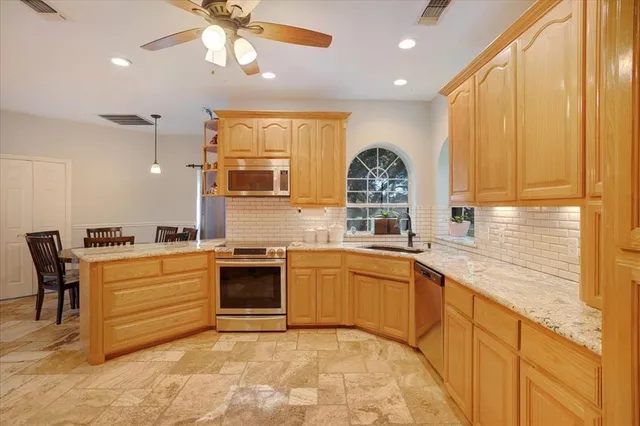 a large kitchen with stainless steel appliances granite countertop a sink and cabinets