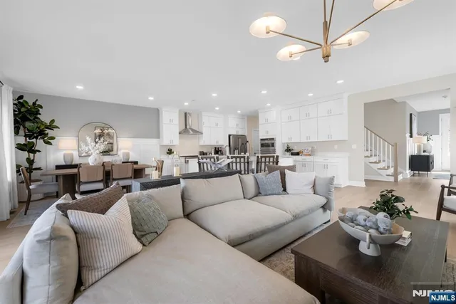 a living room with furniture kitchen view and a chandelier