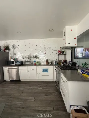 a large kitchen with stainless steel appliances a stove a sink and white cabinets