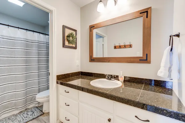 a bathroom with a granite countertop sink and a mirror