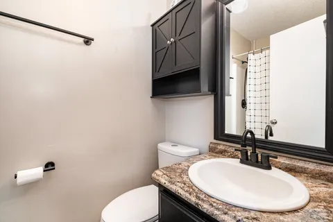 a bathroom with a granite countertop sink a toilet and a mirror