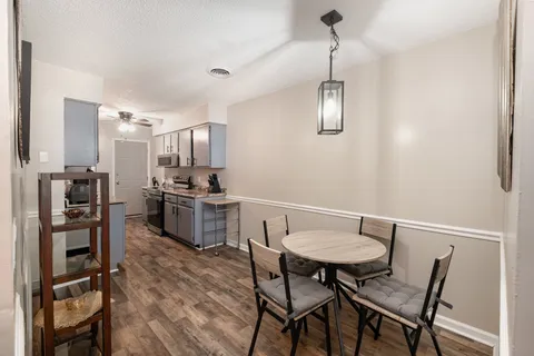 a kitchen with stainless steel appliances a dining table chairs and refrigerator