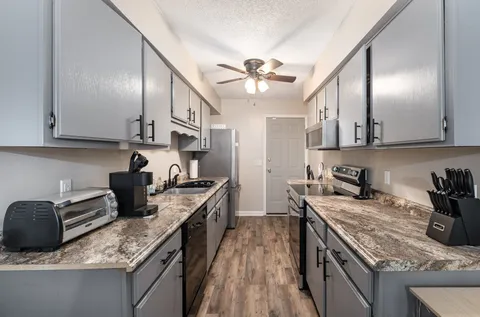 a kitchen with granite countertop kitchen island stainless steel appliances a sink stove top oven and cabinets