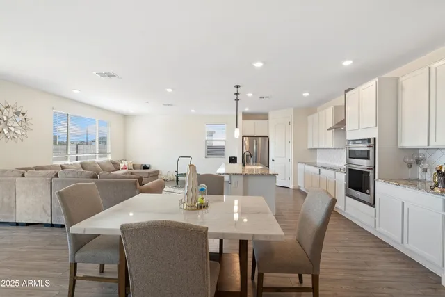 a living room with furniture a wooden floor and a view of kitchen