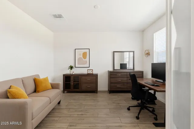 a living room with furniture kitchen view and a wooden floor