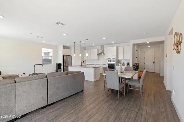 a living room with furniture a wooden floor and a view of kitchen