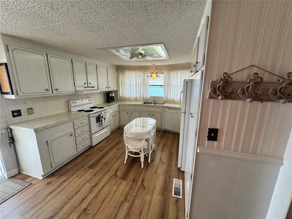 2331 Belleair Road, Unit 804 Clearwater, FL 33764 - Photo 9 of 37 a kitchen with stainless steel appliances granite countertop a refrigerator a sink dishwasher a stove and white countertops with wooden floor