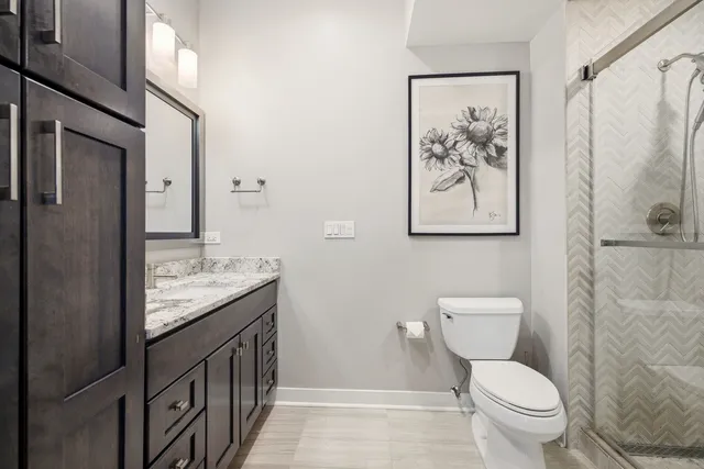 a bathroom with a granite countertop toilet a sink and a shower
