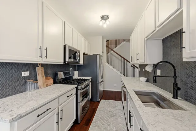 a kitchen with granite countertop a sink a stove and cabinets