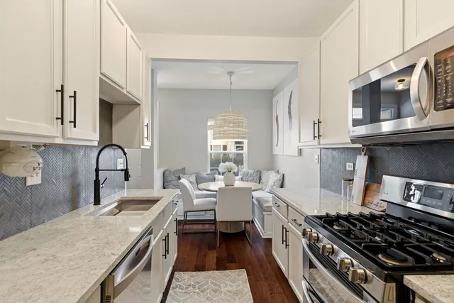 a kitchen with stainless steel appliances granite countertop a stove a sink dishwasher and cabinets with wooden floor