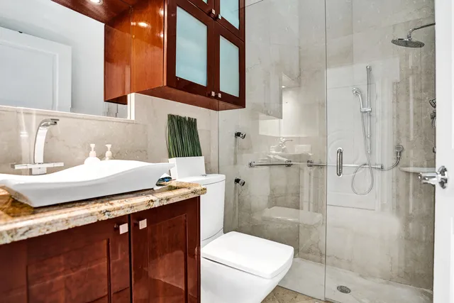a bathroom with a granite countertop sink mirror toilet and shower