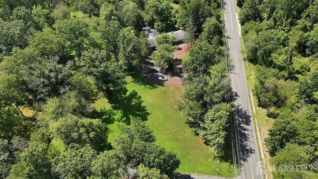 an aerial view of residential house with outdoor space and trees all around