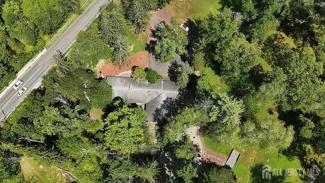 an aerial view of residential house with outdoor space and trees all around