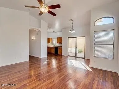 an empty room with wooden floor chandelier ceiling fan and windows