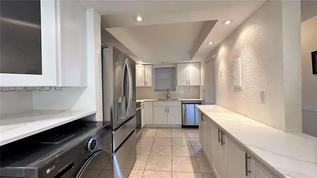 a large kitchen with a large counter top space appliances and cabinets