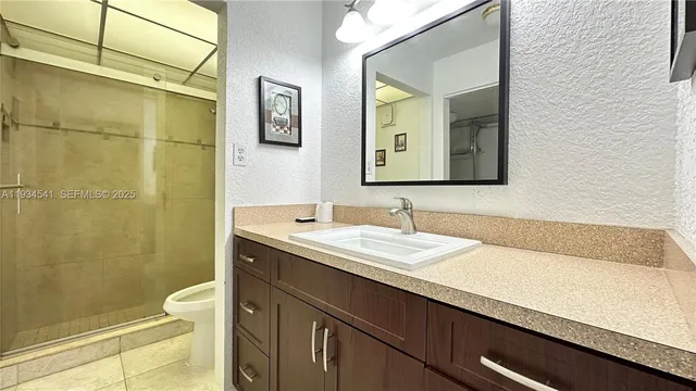 a bathroom with a granite countertop sink a toilet and a mirror