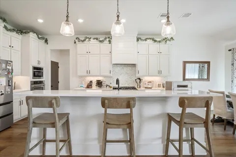 a kitchen with white cabinets and chairs