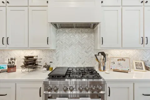 a kitchen with white cabinets and a stove top oven