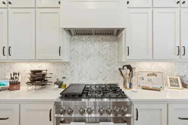 a kitchen with white cabinets and a stove top oven