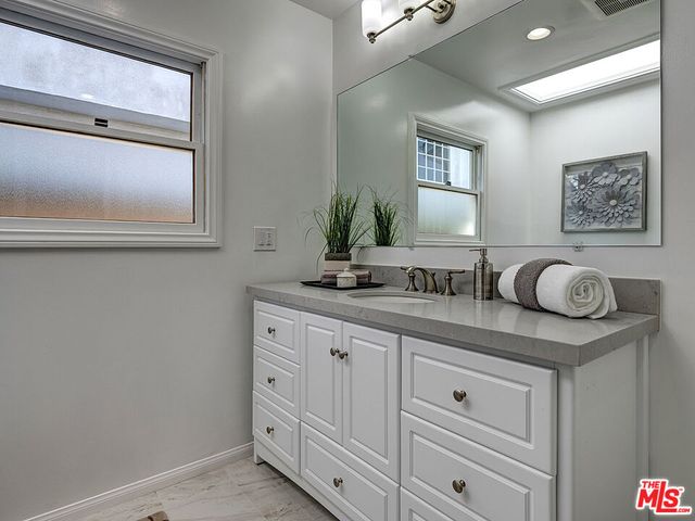 a bathroom with a granite countertop sink mirror and window